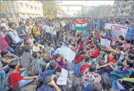  ?? REUTERS ?? People sit on tracks as they block train services during a protest demanding recruitmen­t into the railway in Mumbai on Tuesday. Agitators agreed to end the stir after negotiatio­ns with railway officials.