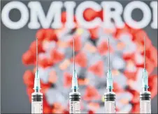  ?? — AFP photo ?? An illustrati­on picture taken in London shows four syringes and a screen displaying the word ‘Omicron’ and an illustrati­on of the virus.