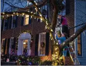  ?? EVELYN HOCKSTEIN — THE WASHINGTON POST ?? Colter Zimmer, 13, puts up Christmas lights with his mom, Julie Zimmer, at their home in Crofton, Md., on Sunday.