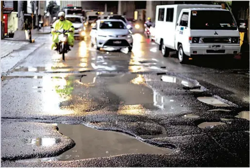  ?? (Jun Ryan Arañas) ?? A BUMPY RIDE – Potholes, gouged by days of continuous rain, riddle a portion of Osmeña Highway in Makati City, clogging traffic, especially during rush hours. Many more streets in Metro Manila were also damaged by the rains.