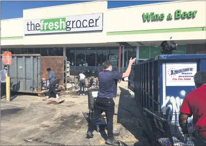  ?? PHOTOS BY PETE BANNAN - MEDIANEWS GROUP ?? The Fresh Grocer had 4 feet of water on Tuesday which ruined most of the stock. Employees spent much of Wednesday morning throwing ruined food into dumpsters.