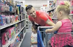  ??  ?? CPL. JORDAN ZIEGLER shops on base with daughters Delilah, left, and Adelaide. Groceries at the commissary are up to 30% less than off base.