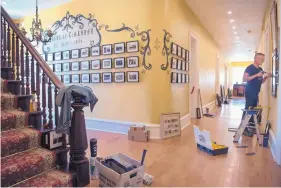  ?? EDDIE MOORE/JOURNAL ?? Kevin Kempton, a designer from Arizona, hangs historical photos in a hall at the St. James Hotel in Cimarron. The hotel’s operations have been significan­tly impacted by the closure of Philmont Scout Ranch for the summer.