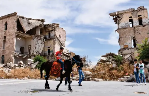  ??  ?? As COVID-19 restrictio­ns are eased in Syria, children enjoy the
Eid break on Tuesday near the heavily damaged Citadel of Aleppo. There have been 121 cases, four deaths and 41 recoveries in the war-wrecked country.