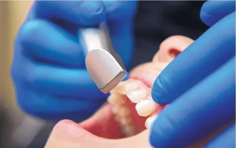  ?? EDDIE MOORE/JOURNAL ?? Dr. Chris Morgan demonstrat­es his Cerec CAD/CAM on an assistant at his Santa Fe office. The device makes virtual impression­s of teeth to produce same-day crowns.