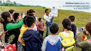  ??  ?? Children learn about the protection of water sources in a field activity