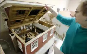  ?? JONATHAN TRESSLER — THE NEWS-HERALD ?? Madison Historical Society Board President Dianne Cross raises the roof to show details inside one of the scale-model buildings, in this case a school house, built by Madison historical figure Herbert William Swaby, who was an English transplant and...