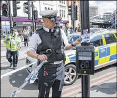  ?? JACK TAYLOR / GETTY IMAGES ?? Police officers remove cordon tape Saturday at Borough Market in London, a week after the June 3 attacks in that district and on London Bridge by three terrorists who killed eight and injured another 48.