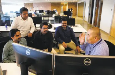  ?? Michael Macor / The Chronicle ?? Robinson Leung (right) talks with a team of Accela engineers at the company’s office in San Ramon.