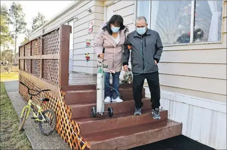  ?? Gary Coronado Los Angeles Times ?? MARIA MARIN, 58, helps her husband, David, 56, with his oxygen tank at their trailer home in Corning. David spent 48 days in the ICU.