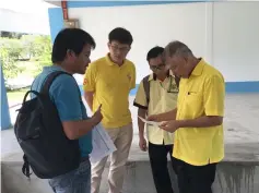  ??  ?? Ting (left) goes through the update report on the RTP project at SJKC Tukau during the inspection. With him are the representa­tives of JKR and the project’s contractor.