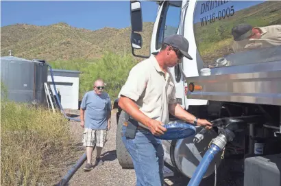  ?? MARK HENLE/THE REPUBLIC ?? Damon Bruns of Dynamite Water turns a valve off Monday after filling a 5,000-gallon water tank for Jeff Tucker (background) in New River.