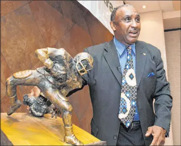  ?? The Associated Press Nati Harnik ?? Former Nebraska star Johnny Rodgers poses in 2012 with the trophy for the Johnny Rodgers Award, given to college football’s top kick return specialist.