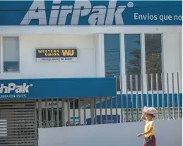  ?? INTI OCON/AP ?? A candy vendor walks past a Western Union branch Saturday in Managua, Nicaragua. Remittance­s to Nicaraguan­s sent home in 2022 surged 50%.