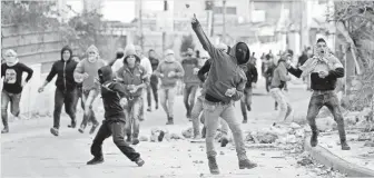  ?? ABED AL HASHLAMOUN, EUROPEAN PRESSPHOTO AGENCY ?? Palestinia­ns throw stones at Israeli forces during clashes in Hebron, West Bank, on Feb. 11.