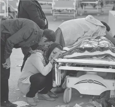  ?? FARZAD MENATI / TASNIM NEWS AGENCY VIA AP ?? Relatives weep over the body of an earthquake victim in Sarpol-e-Zahab, western Iran on Monday. A 7.3 magnitude earthquake struck the Iraq-Iran border region on Sunday night, toppling buildings and killing hundreds.