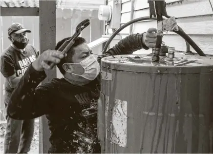  ?? Brett Coomer / Staff photograph­er ?? Marvin Mariquin dismantles Kenneth Castilow’s damaged water heater Saturday in Sunnyside. The nonprofit Houston Health Foundation plans to make repairs at 200 to 300 homes thanks to donations.