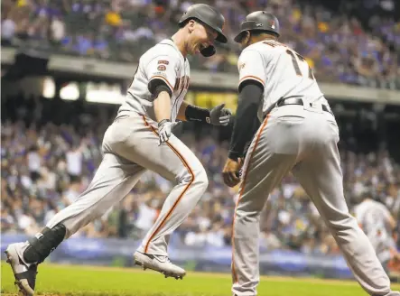  ?? Morry Gash / Associated Press ?? Giants’ Buster Posey is happy to see firstbase coach Jose Alguacil after smashing a grand slam in the 10th inning.