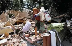  ?? PICTURE: REUTERS ?? LEFT: A woman carries goods from the ruins of her house in Kayangan district after the earthquake hit on Sunday in North Lombok in Indonesia.