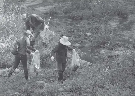  ?? Photo by Jean Nicole Cortes ?? CLEAN-UP. Volunteers work together to gather trash from the polluted Balili River drive in a bid to clean and save our inland waterways. Another clean-up drive will take place on September 20 at AgnoAmbala­ngo, Asin- Galiano, Balili and Bued Rivers.