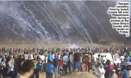  ?? AP ?? Teargas canisters fired by Israeli troops fall over Palestinia­ns during a protest at the Gaza Strip’s border with Israel on Friday.