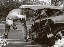  ?? Ringo H.W. Chiu / Associated Press ?? A law enforcemen­t officer looks over the SUV driven by Tiger Woods in a rollover crash Tuesday in Rancho Palos Verdes, Calif.