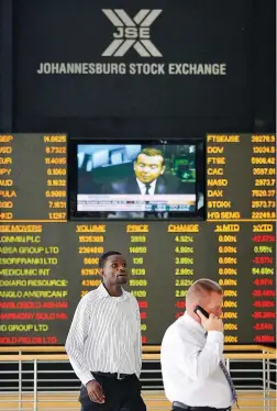  ?? PICTURE: REUTERS ?? Two men walk past an electronic board displaying movements in major indices at the JSE in Sandton. The writer asks if white monopoly capital is racialised in South Africa.