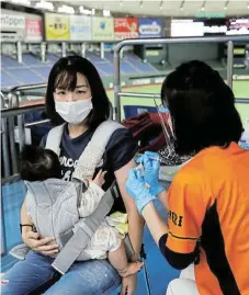  ?? /Reuters ?? Shot treatment: A woman receives a Covid-19 jab at the Tokyo Dome, in Tokyo, Japan, as the country ramps up its vaccinatio­n rollout.