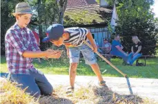  ??  ?? Auch Kinder dürfen vor historisch­er Kulisse den Dreschfleg­el schwingen – so wie es viele Jahrhunder­te lang nach der Getreideer­nte üblich war.