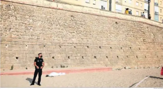  ?? JESÚS MARÍN ?? Una sábana cubre el cuerpo sin vida del hombre que se precipitó ayer a la playa Santa María del Mar desde la muralla.