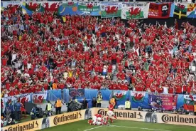 ?? Photograph: Hassan Ammar/AP ?? Wales fans rise to celebrate Hal Robson-Kanu’s late winner against Slovakia at Euro 2016, but the 2022 World Cup has not captured imaginatio­ns in the same way.