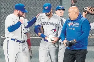  ?? JIM MONE THE ASSOCIATED PRESS ?? Blue Jays left-fielder Lourdes Gurriel Jr., second from left, gets medical attention after his right hand was accidental­ly stepped on by teammate Randal Grichuk, rear, during the fifth inning.