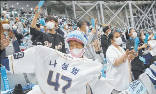  ?? Ahn Young-joon The Associated Press ?? Masked fans cheer during Game 4 of the Korea Baseball Organizati­on’s championsh­ip round Saturday between the Doosan Bears and NC Dinos in Seoul. South Korea has relied on a test-and-quarantine campaign and mask-wearing over lockdowns.