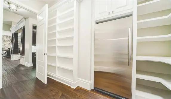  ?? HOMES BY US ?? This walk-through pantry featuring solid shelving offers a spacious storage solution.
