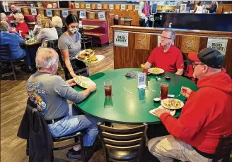  ?? NICK GRAHAM / STAFF ?? Waitress Mya Hogeback serves food to Bruce Taylor (left), Brian Taylor and Rod McGaha (right) on Thursday at Putters Sports Grill in Liberty Twp. Owner Jan Collins closes the restaurant every Monday to save on overhead.