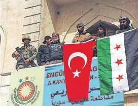  ?? THE ASSOCIATED PRESS] [HASAN KIRMIZITA/DHA-DEPO PHOTO VIA ?? A Turkish and a Turkey-backed Free Syrian Army soldier wave Turkish and FSA flags early Sunday in the city center of Afrin, northweste­rn Syria.