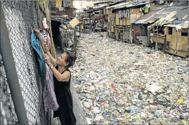  ??  ?? JUST RUBBISH: Manila housewife Perigrina Santos, above, collects her laundry next to a rubbish-filled creek