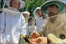 ?? Democrat-Gazette file photo/BENJAMIN KRAIN ?? Jon Zawislak (right) marks the queen bee while helping Aiden McCarthy, Desiree Baxter, Xander Baxter, Calvin Zawislak and other members of a Cooperativ­e Extension Service class on beekeeping at Two Rivers Park in 2013.