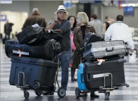  ?? THE ASSOCIATED PRESS FILE PHOTO ?? Travelers walk through baggage claim at O’Hare Internatio­nal airport in Chicago, Ill. More people than ever before are buying travel insurance to protect their vacations. So far this year, AAA’s domestic and internatio­nal travel insurance sales are up 20 percent over the same period last year. According to a recent AAA travel survey, nearly four in 10 Americans — or 38 percent — are likely to purchase insurance for internatio­nal trips.