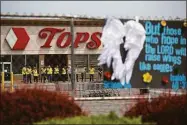  ?? Joshua Bessex / Associated Press ?? Investigat­ors stand outside during a moment of silence for the victims of the Buffalo supermarke­t shooting outside the Tops Friendly Market on Saturday in Buffalo, N.Y. Tops was encouragin­g people to join its stores in a moment of silence to honor the shooting victims Saturday at 2:30 p.m., the approximat­e time of the attack a week earlier.