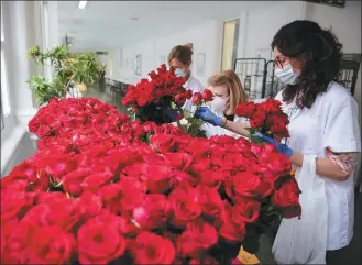  ?? PHOTO BY XINHUA ?? Medical workers take time out to admire roses left at a hospital on Saint George’s Day on Thursday in Barcelona, Spain. The holiday for Barcelona’s patron saint usually sees the streets filled with throngs of people exchanging books and flowers with their loved ones. But this year, it was marked with a twist amid the coronaviru­s pandemic.
