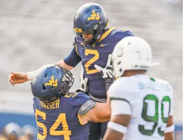  ?? BEN QUEEN/USA TODAY SPORTS ?? West Virginia’s Jarret Doege gets a lift from Zach Frazier after a touchdown pass.