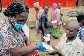  ?? /Reuters ?? Crisis response: A volunteer distribute­s food and water to the underprivi­leged and homeless, as Ghana enforces a partial lockdown in Accra and Kumasi.