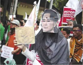  ??  ?? JAKARTA: In this Nov 25, 2016, file photo, a Muslim woman wears a mask of Myanmar’s Foreign Minister Aung San Suu Kyi during a rally against the persecutio­n of Rohingya Muslims, outside the Embassy of Myanmar. — AP