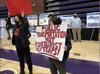  ?? STEVE SCAUZILLO — STAFF ?? Two protesters with the Stop The Gondola group hold signs during a public hearing on the proposed aerial tram project that would link Union Station with Dodger Stadium and go over Chinatown. The hearing was held at Cathedral High School's gymnasium Jan. 12.