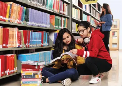  ??  ?? COLLABORAT­IVE EFFORT Students going over books in the library (left): finishing a project (above)