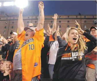  ?? KARL MERTON FERRON / BALTIMORE SUN PHOTO ?? Alanna Miller, 5, bottom left, her father, Bob Miller, middle, of Middle River, and Kayla Stoner of Etters, Pa., react while Oriole Steve Pearce rounds the bases after connecting for a three-run home run.