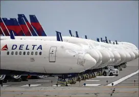  ?? CHARLIE RIEDEL/AP ?? Mothballed Delta jets sit on a closed runway in May in Kansas City, Missouri. Delta last week reported a $755 million loss for the fourth quarter, which brings its loss for all of 2020 to more than $12 billion. And Delta gave a cautious outlook for the first quarter of 2021, saying it expects to lose $10 million to $15 million a day for the next three months.