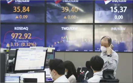  ??  ?? A currency trader wearing a face mask talks with his colleague at the foreign exchange dealing room of the KEB Hana Bank headquarte­rs in Seoul, South Korea on April 6, 2021. Asian shares were mixed Tuesday after a Wall Street rally that reflected some optimism about the economy recovering from the damage of the coronaviru­s pandemic. (AP)