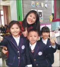  ?? DAVID BLAIR / CHINA DAILY ?? Wang Jing, English teacher of second-graders at the Tsinghua-affiliated elementary school, poses with students.